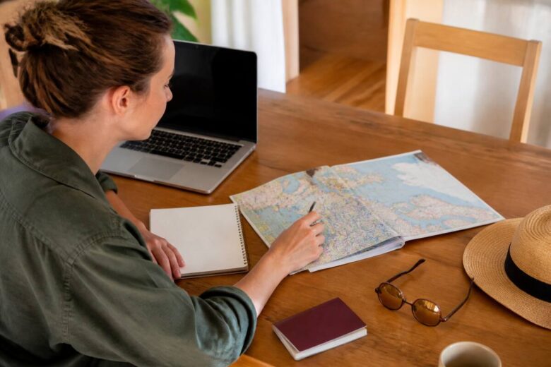 Reiziger vergelijkt vakanties met laptop, kaart en notitieboek